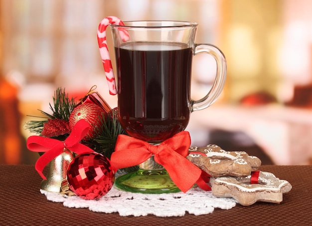 Warme smakelijke drank met kerstsnoep en andere versieringen op lichte achtergrond