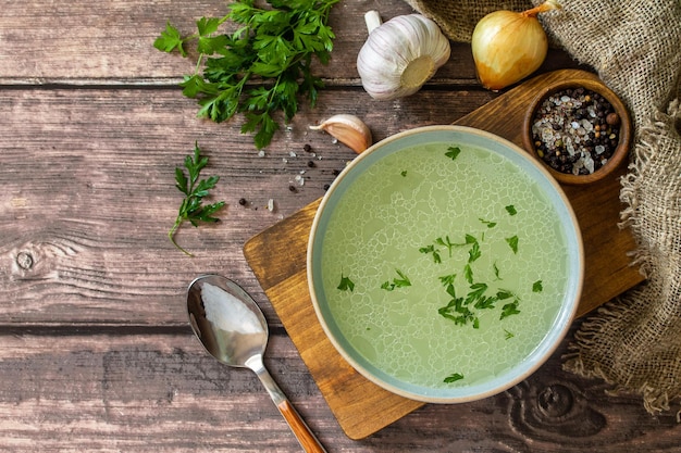 Warme vleesrijke bouillon met kruiden op een rustieke tafeltop, vlakke achtergrond, kopieerruimte.