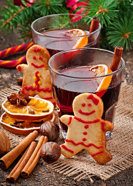 Warming mulled wine, spices and gingerbread cookie on a wooden background in rustic style