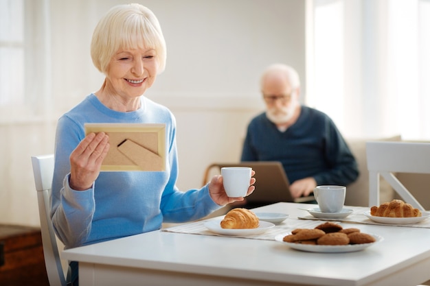 Warming up. Grandmother drinking her coffee, eating croissant and planning her day before arriving of her grandchildren