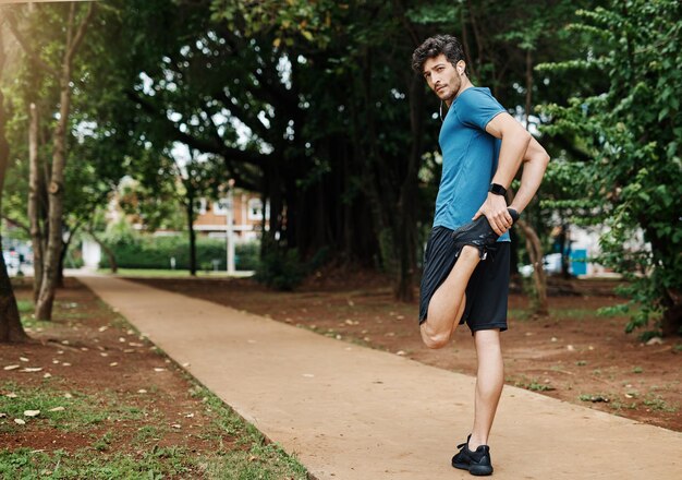 Warming up to keep up Shot of a sporty young man stretching his legs while exercising outdoors