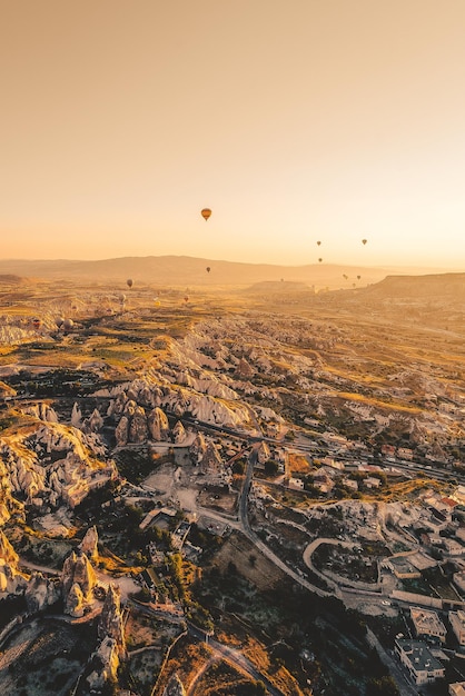 Warmluchtballonnen vliegen over het landschap van cappadocia bij zonsondergang