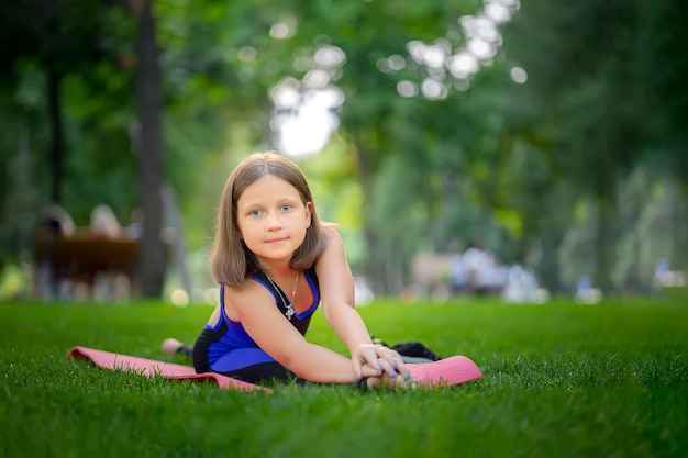 Warmup in the park girl doing stretching Sitting in twine on the lawn in the park