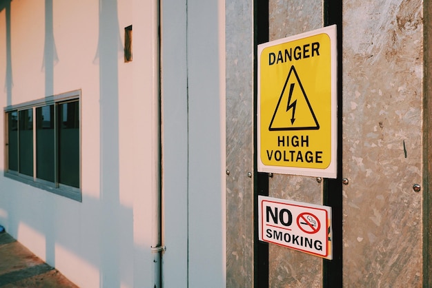 warning danger high voltage sign and no smoking label on steel pipe cover outside of building