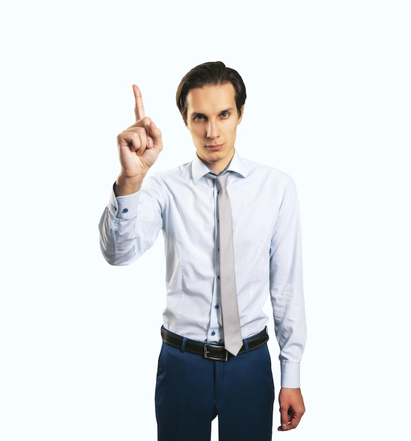 Warning and notification concept with young man with rising up index finger isolated on light grey wall background closeup