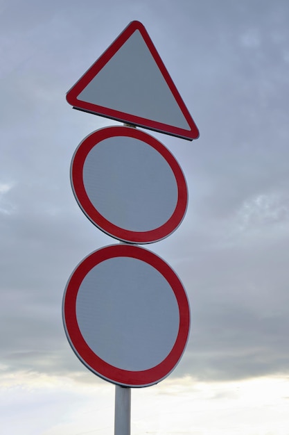 Warning road sign against a cloudy sky with clouds.