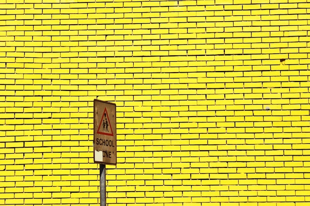 Photo warning road sign against yellow brick wall