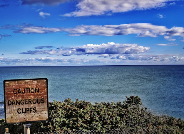 Photo warning sign on calm sea against the sky