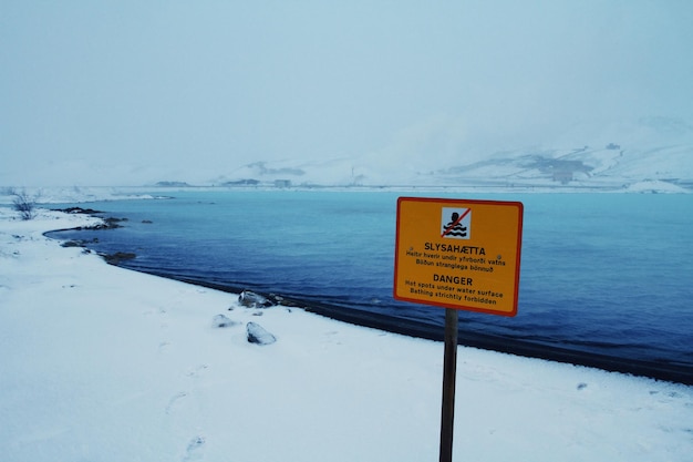 Photo warning sign on lakeshore during winter