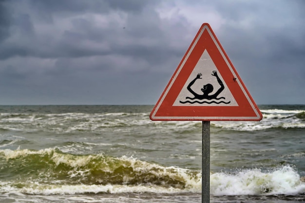 Photo warning sign on sea against sky