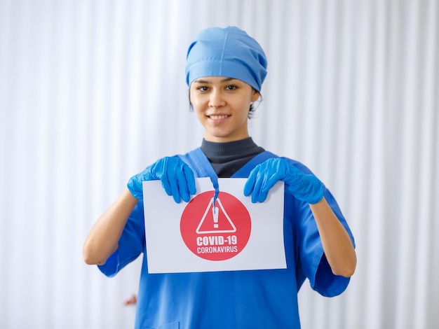 Il segnale di avvertimento è stato fatto a pezzi da un bel dottore felice in uniforme ospedaliera blu su sfondo sfocato quando la pandemia di coronavirus finisce la vita normale è tornata