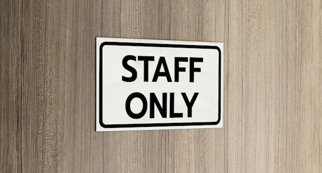 Photo warning silver stainless steel sign with character black message staff only in front of the wooden door