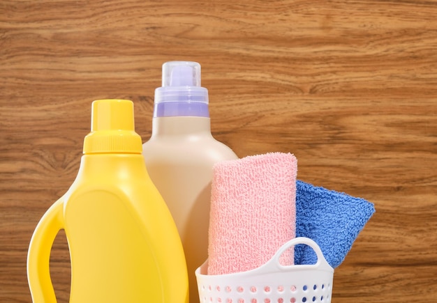 Was- en dienstmeisjeconcept Wasmiddelen op een houten achtergrond Wasmand met blauwe en roze handdoek