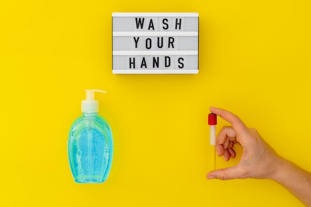 Wash your hands lightbox with medical mask, lighid soap and medical gloves. Top view on yellow background