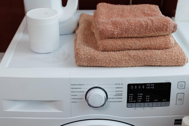 Washed dry clean towels on washing machine puting stack of fresh terry bath towels