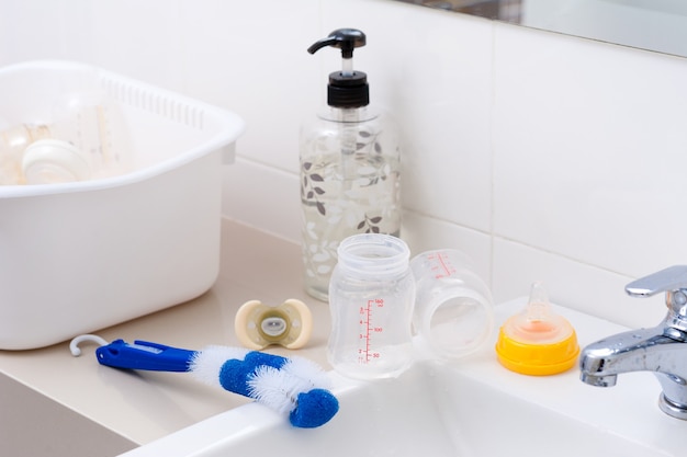 Washing baby bottles and nipples with soft bottle brush and dishwashing liquid