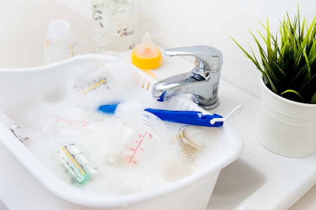 Washing baby bottles and nipples with soft bottle brush and dishwashing liquid