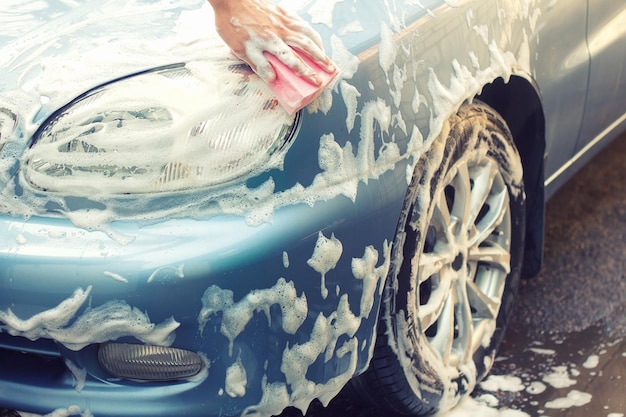 Washing the car by hand with soapy sponge