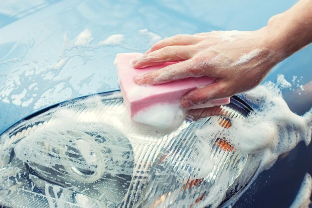 Washing the car by hand with soapy sponge