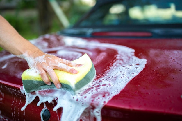 Lavare l'auto a mano con spugna e shampoo l'auto è rossa