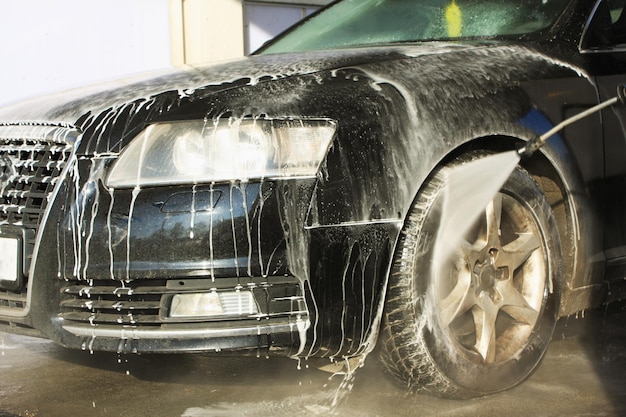 流れる水と泡で車を洗う