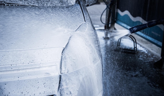 Washing car with soap. Close up clean car concept at car wash.