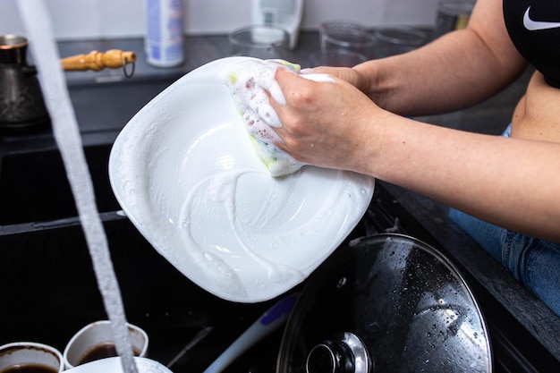 Foto lavare i piatti con mani femminili