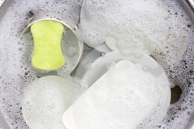 Washing dishes, Close up of utensils soaking in kitchen sink.