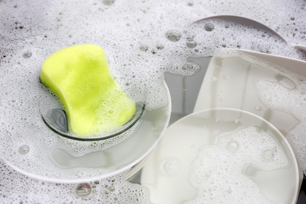 Washing dishes, Close up of utensils soaking in kitchen sink.