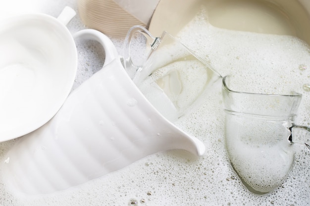 Washing dishes, Close up of utensils soaking in kitchen sink.