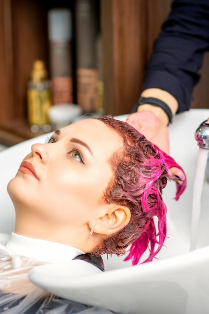 Photo washing dyed female hair a young caucasian woman having her hair washed in a beauty salon