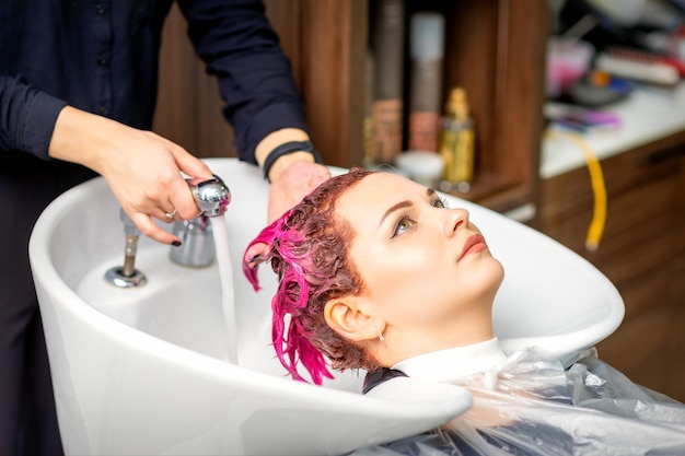 Lavare i capelli femminili tinti una giovane donna caucasica che si fa lavare i capelli in un salone di bellezza