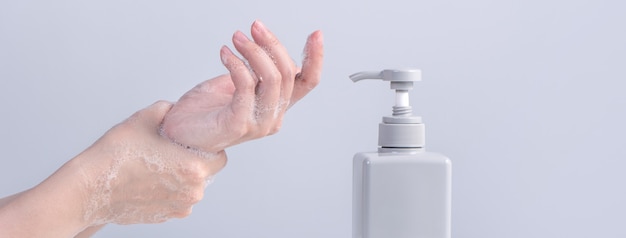 Photo washing hand. asian young woman using liquid soap to wash hands, concept of hygiene to stop spreading coronavirus isolated on gray white background, close up.