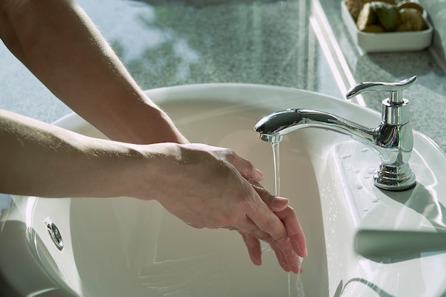 Washing hand under the faucet with water