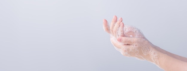 사진 손을 씻는 아시아 젊은 여성은 회색 흰색 배경에 격리된 대유행 코로나바이러스를 보호하기 위해 손을 씻기 위해 액체 비누를 사용합니다.