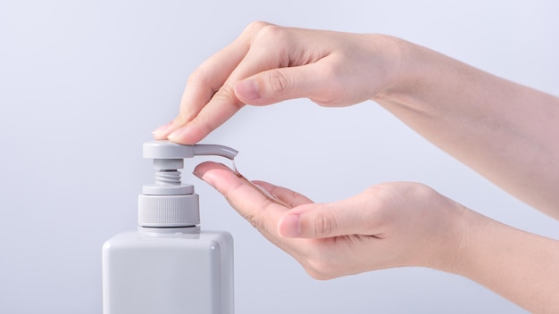 Washing hands Asian young woman using liquid soap to wash hands concept of hygiene to protective pandemic coronavirus isolated on gray white background close up