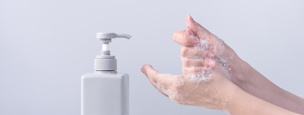 Washing hands Asian young woman using liquid soap to wash hands concept of hygiene to protective pandemic coronavirus isolated on gray white background close up