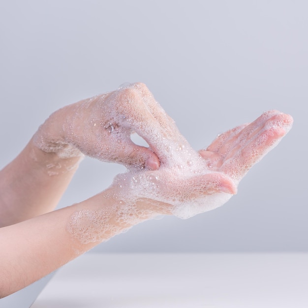 Washing hands Asian young woman using liquid soap to wash hands concept of hygiene to protective pandemic coronavirus isolated on gray white background close up