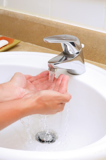 Washing hands before eating in white sink.