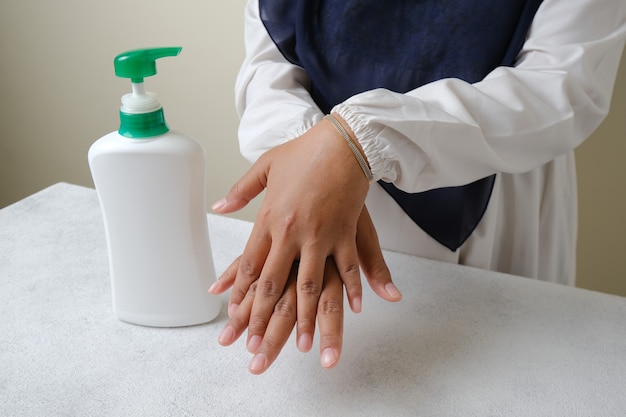 washing hands by liquid soap or alcohol gel from pump bottle hygiene and health care concept