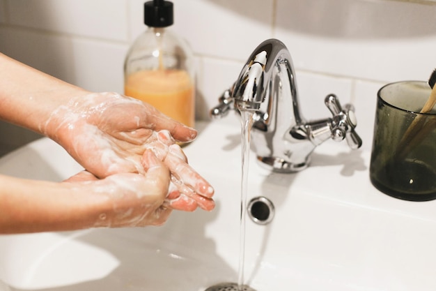 Washing hands hands washing with soap foam on background of\
flowing water in bathroom rubbing palms prevention of flu disease\
personal hygiene cleaning hands to prevent coronavirus\
epidemic