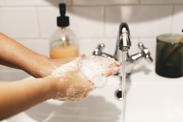 Washing hands hands washing with soap foam on background of
water flowing from faucet prevention of flu disease personal
hygiene how to clean hands right