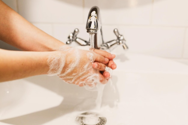 Washing hands hands washing with soap foam on background of\
water flowing from faucet prevention of flu disease personal\
hygiene how to clean hands right