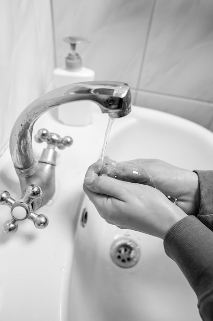 コロナウイルス予防のために石鹸男で手をこすりながら手を洗う白黒写真