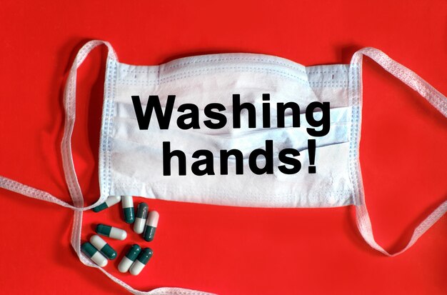 Washing hands - text on a protective face mask, tablets on a red background