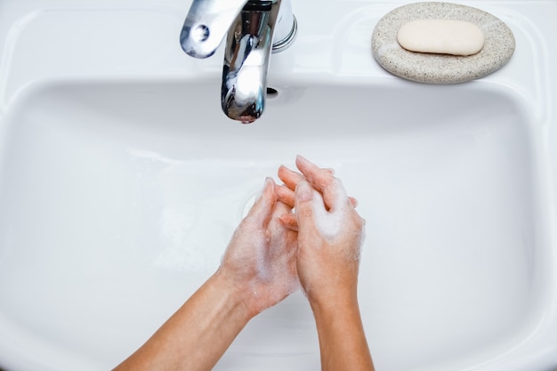 A  Washing hands with soap under the faucet with water