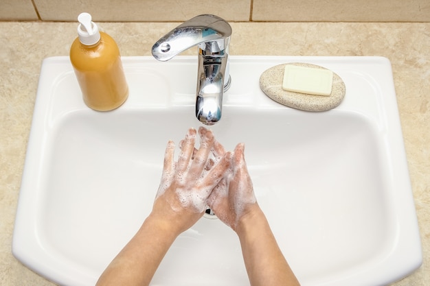 A Washing hands with soap under the faucet with water