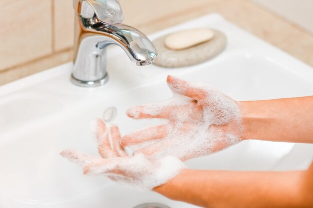 A  Washing hands with soap under the faucet with water