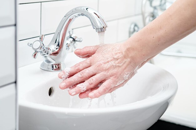 Washing hands with soap under running water to protect against a dangerous virus in the bathroom