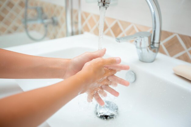 Washing hands with soap under the tap with water the child washes his hands the concept of hygiene